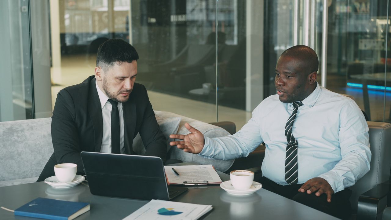 Two businessmen in a strategic discussion over coffee in a modern office setting.